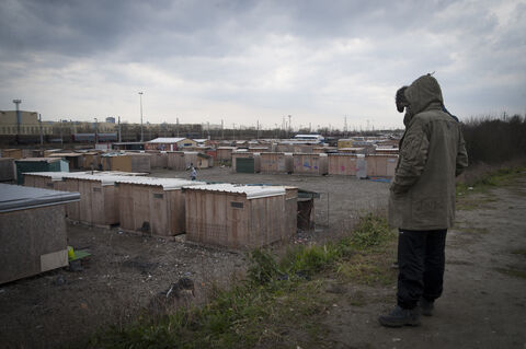  The Grande Synthe camp, the only humanitarian camp in France, a few days from the first year of its opening (March 7, 2017). Open following the closure of the Jungle in Calais to welcome migrants. Man staring at the camp. GRande Synthe. France. 2017