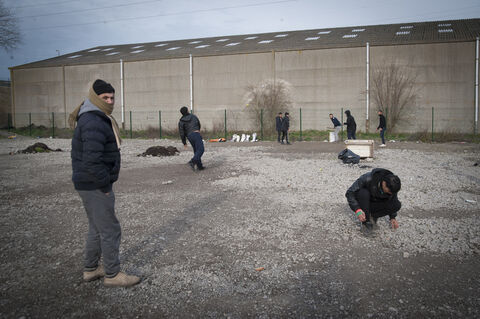  The Grande Synthe camp, the only humanitarian camp in France, a few days from the first year of its opening (March 7, 2017). Open following the closure of the Jungle in Calais to welcome migrants. A group of men playing and watching a cricket game. Grande Synthe. France.2017
